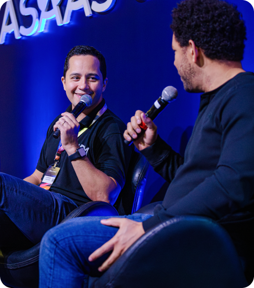 Dois palestrantes conversando e sorrindo enquanto estão sentados em cadeiras do palco Speed Talking